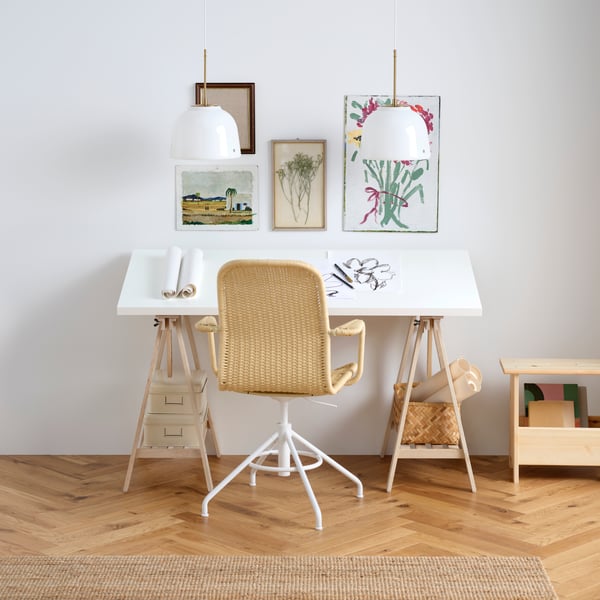 A white LAGKAPTEN tabletop on birch MITTBACK trestles, with a STIGBYGEL swivel chair and art supplies on the desk.