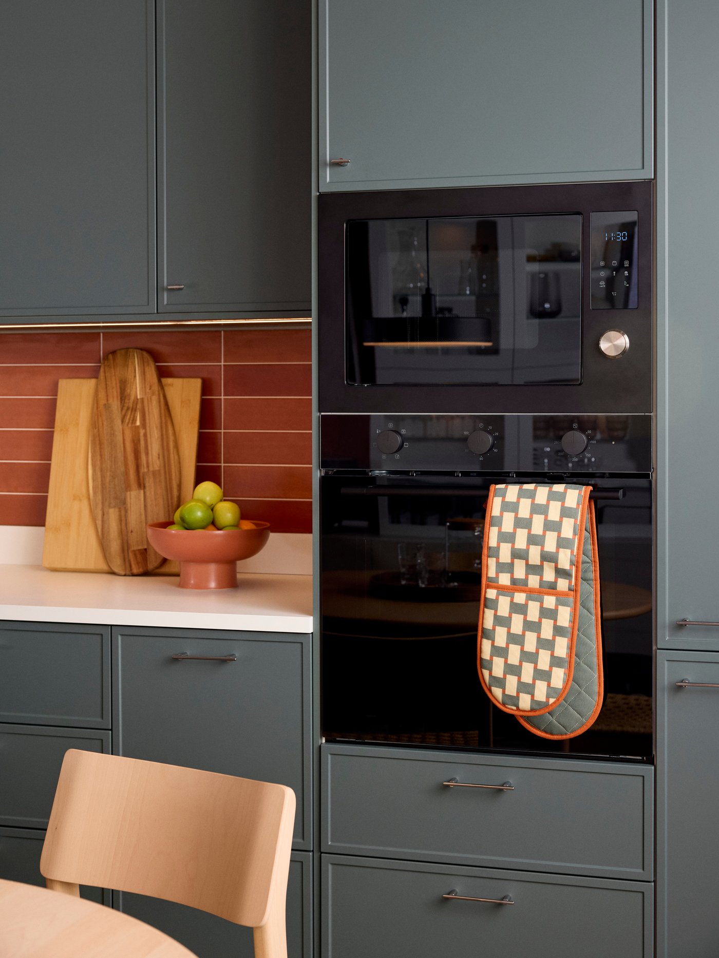A high cabinet with a black modern microwave and an oven, with ASPUDDEN dark grey-green doors.