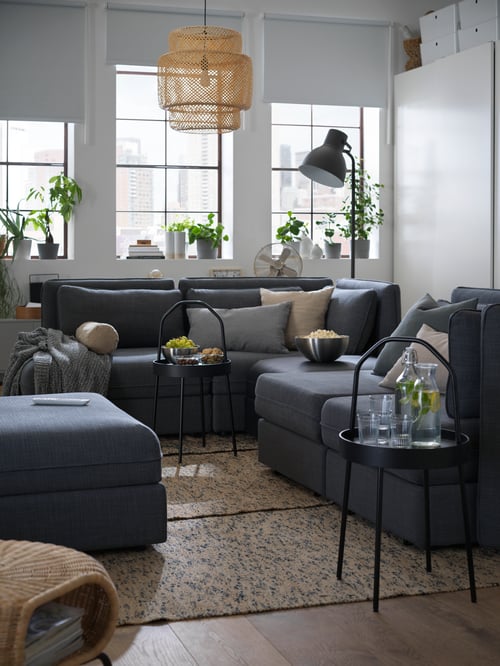 Living room with 2 round side tables made of wood and steel between a 4 seat modular sofa with 3 sofa beds and a seat module.