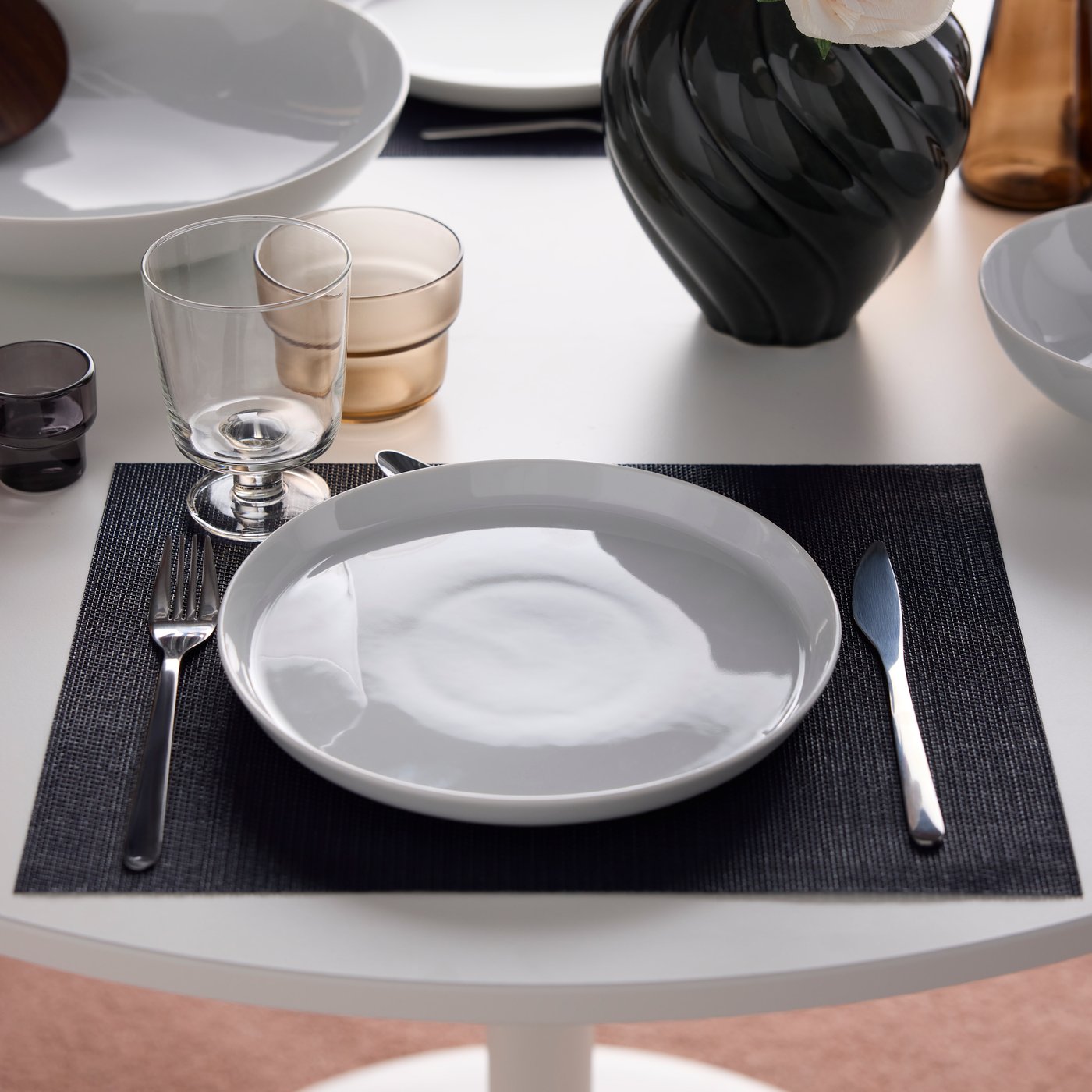 Een couvert met een IKEA 365+ bord, een IKEA 365+ beker en PRAKTBOTIA bestek en een lichtbruin OLIVTRAST glas.