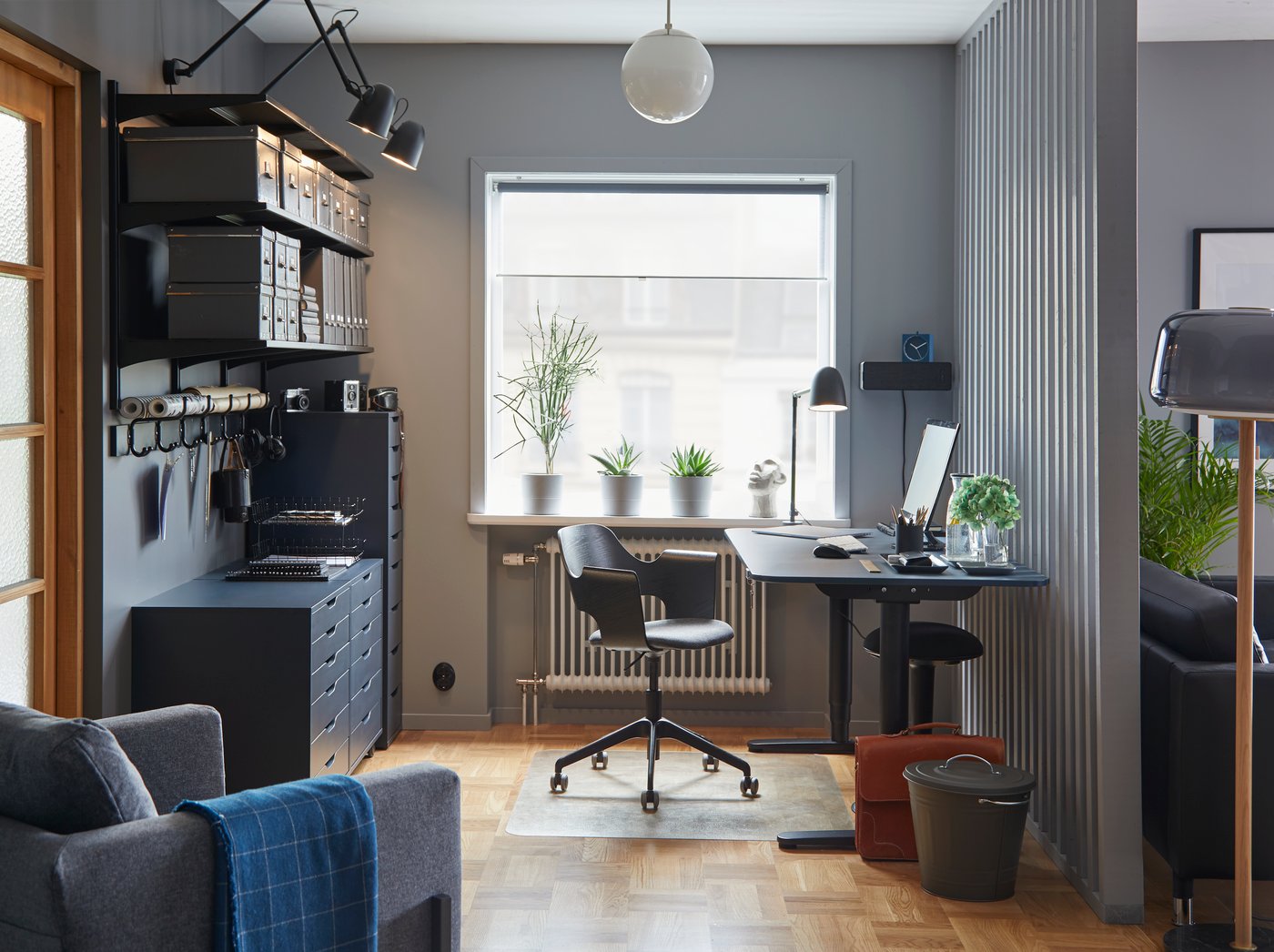 Una scrivania per seduta attiva BEKANT linoleum blu/nero in uno spazio di lavoro dai colori coordinati con una sedia riunioni e delle cassettiere.