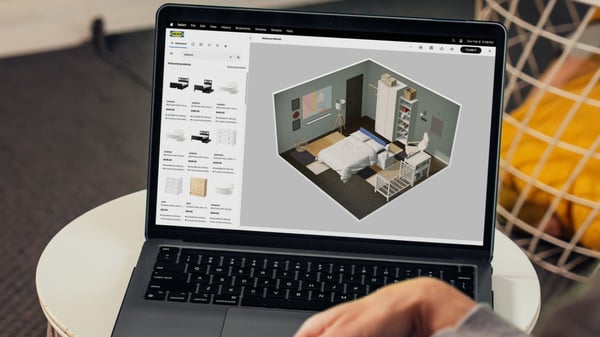 A person is sitting at their laptop and looking at a bedroom they have designed in IKEA Kreativ
