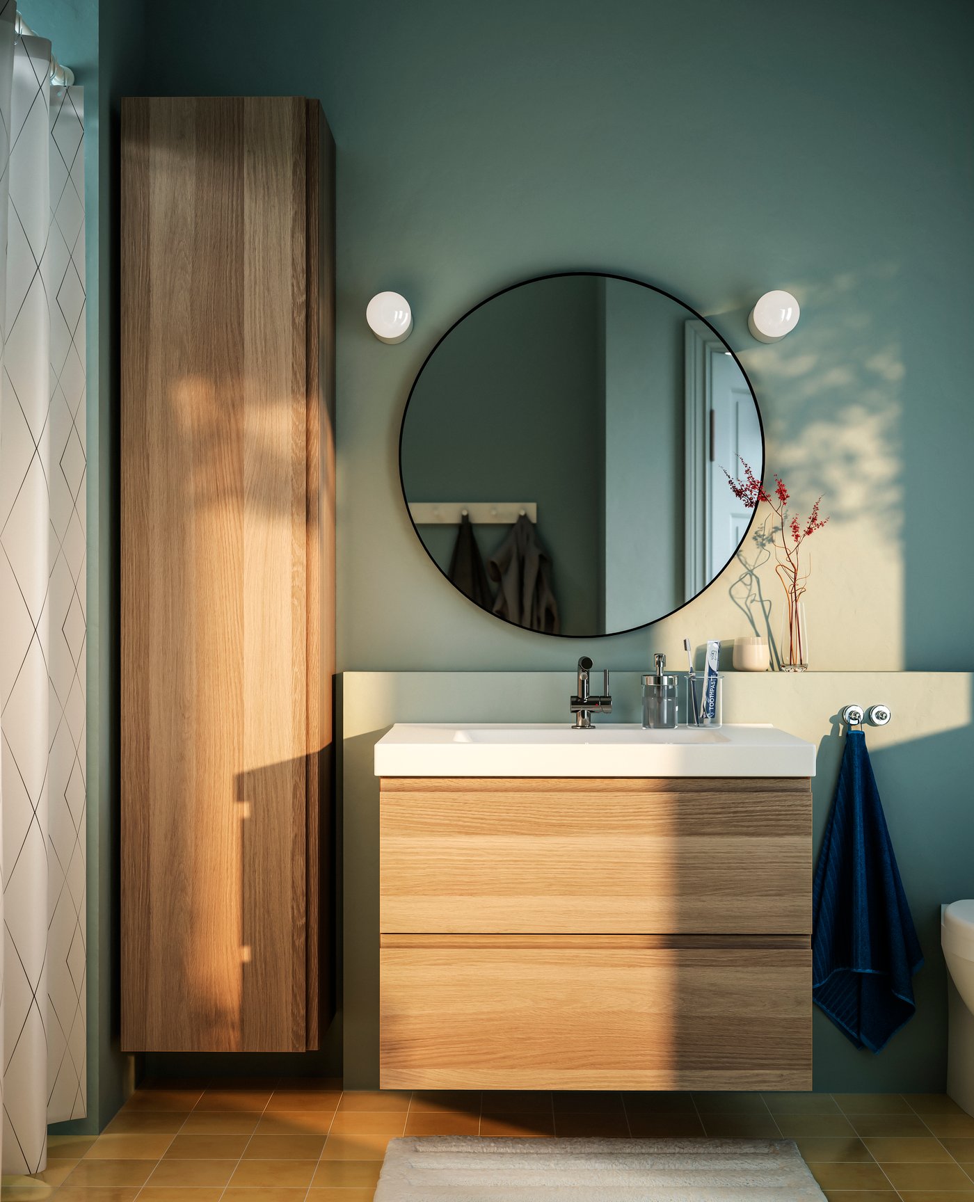 A bathroom with a black round LINDBYN mirror above a wooden wash‑basin cabinet.