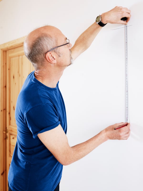 A man measuring a wall.