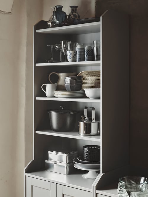 Esszimmer mit einem HAUGA Hochschrank mit 2 Türen, u. a. mit STRIMMIG Schüsseln, einem VARDAGEN Topf mit Deckel und einem METALLISK Wasserkessel.