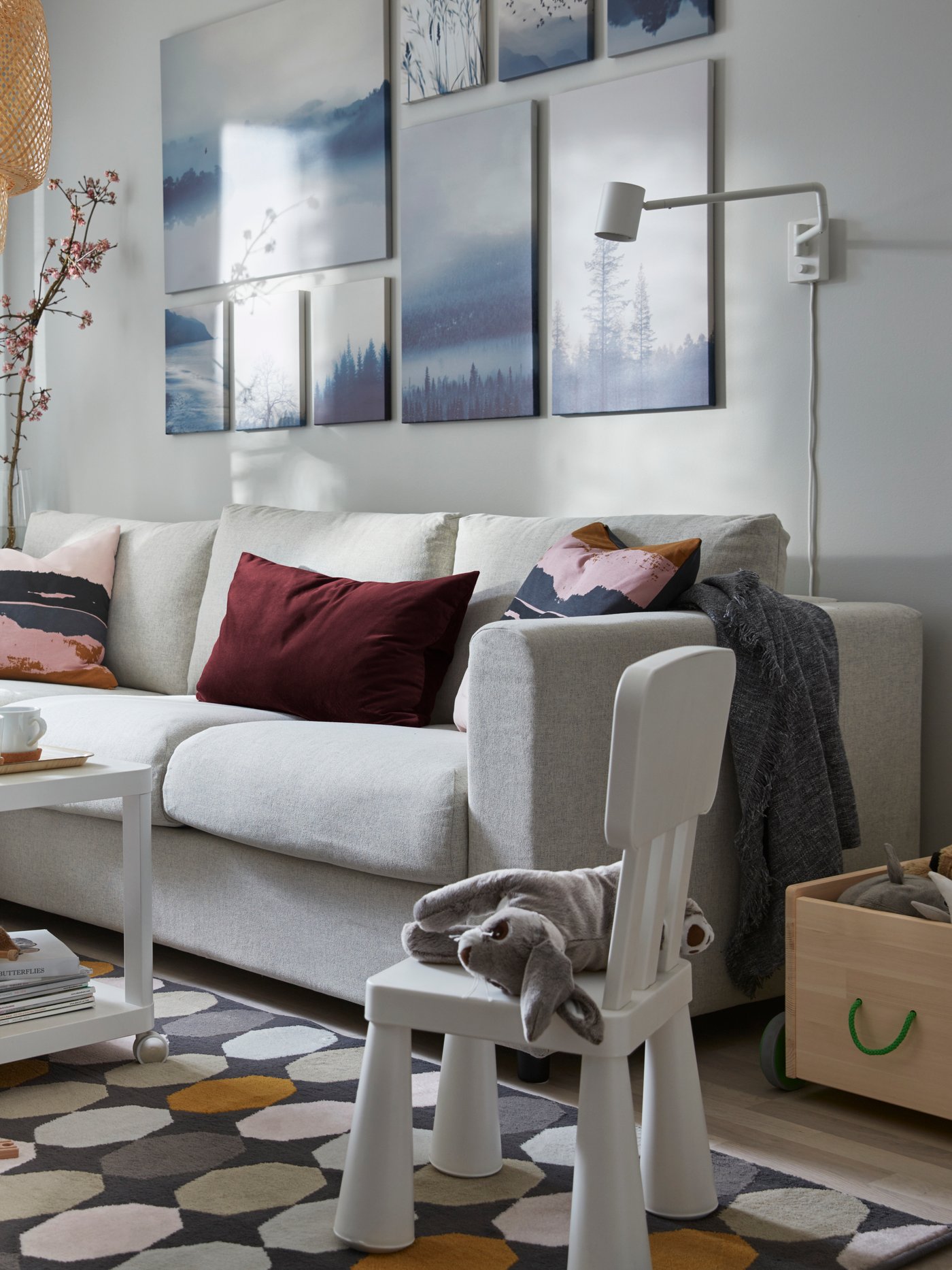 Set de 9 cuadros GRÖNBY de un paisaje azul y blanco, en la pared de una sala sobre un sofá.