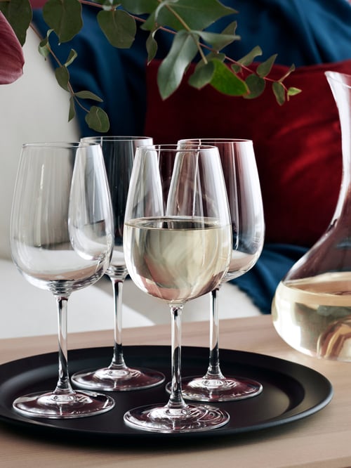 Four STORSINT wine glasses on a black tray next to a wine carafe.