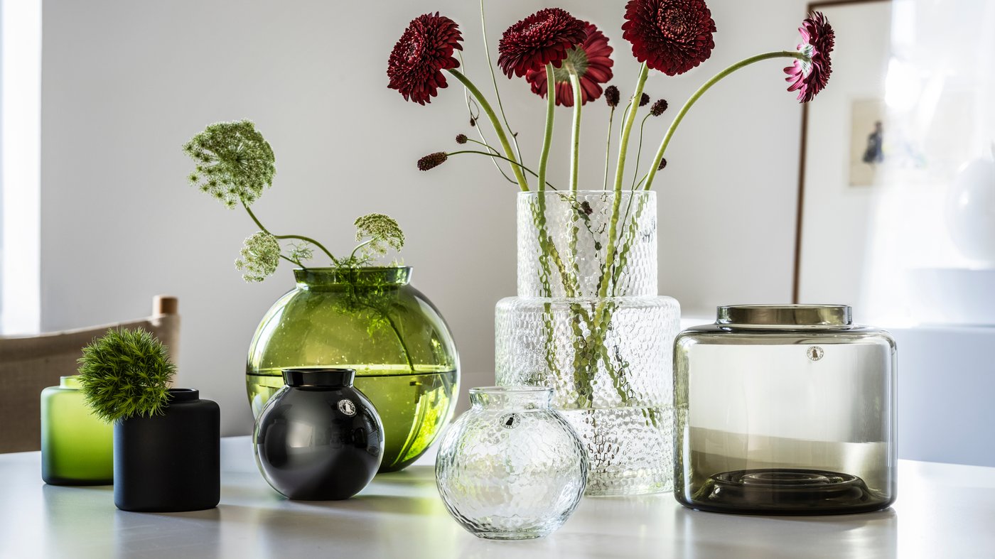 KONSTFULL vases in glass with flowers on a white table in bright room.