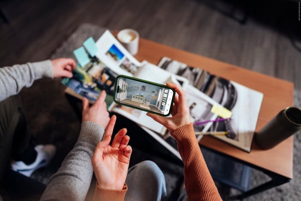 Close up of the hands of two people designing a room on a mobile phone.