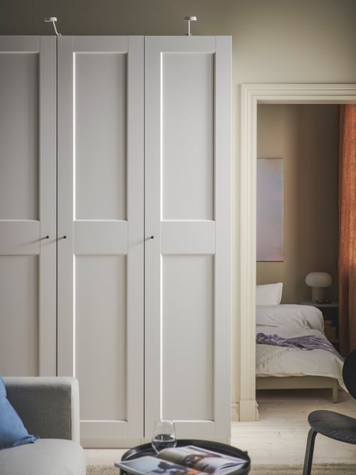 Living room with a white wardrobe combination made of wood placed next to a tray table and a 2-seat sofa bed.