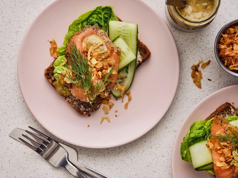 Smørrebrød with salmon & mustard sauce on a pink plate.