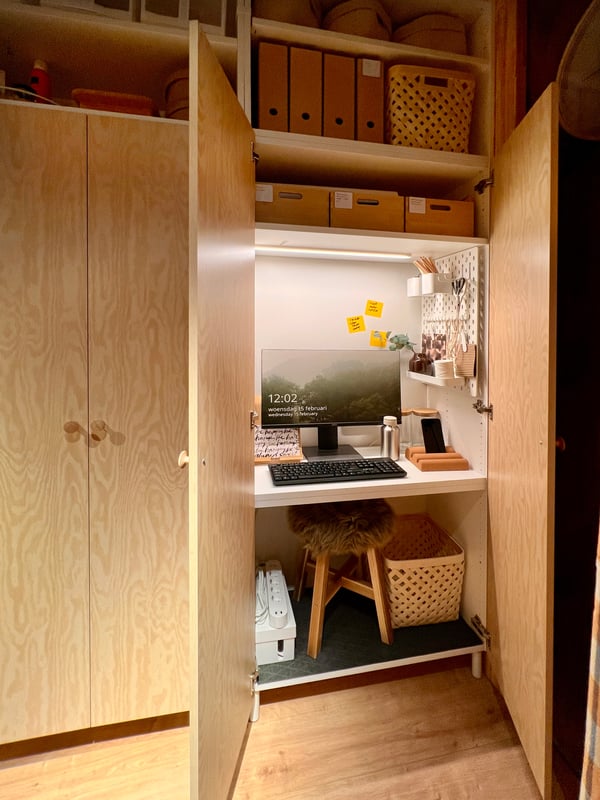 Large cupboard doors behind which is a workplace with a table and a removable stool
