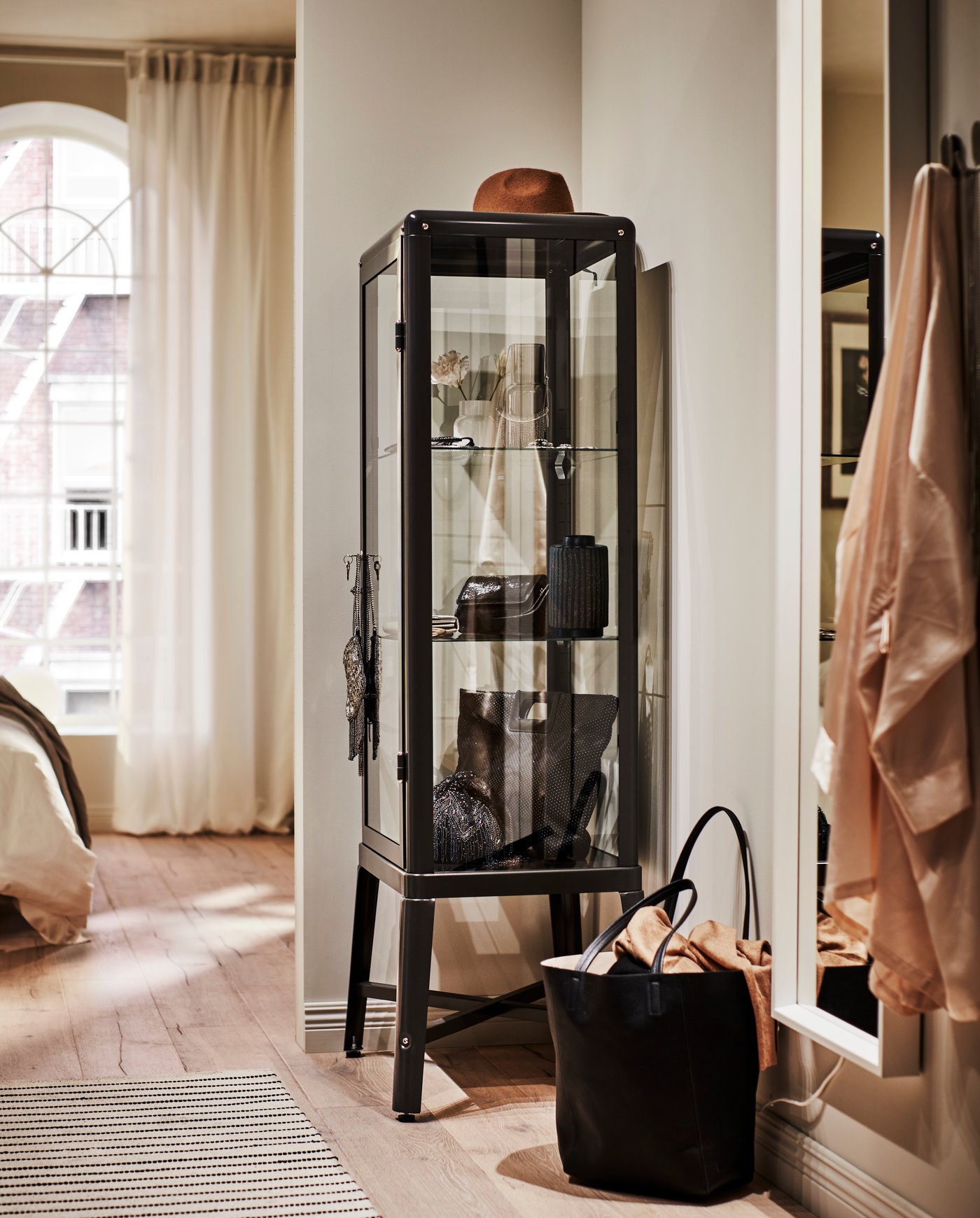 Ein dunkelgrauer FABRIKÖR-Schrank mit Glastüren im Schlafzimmer.