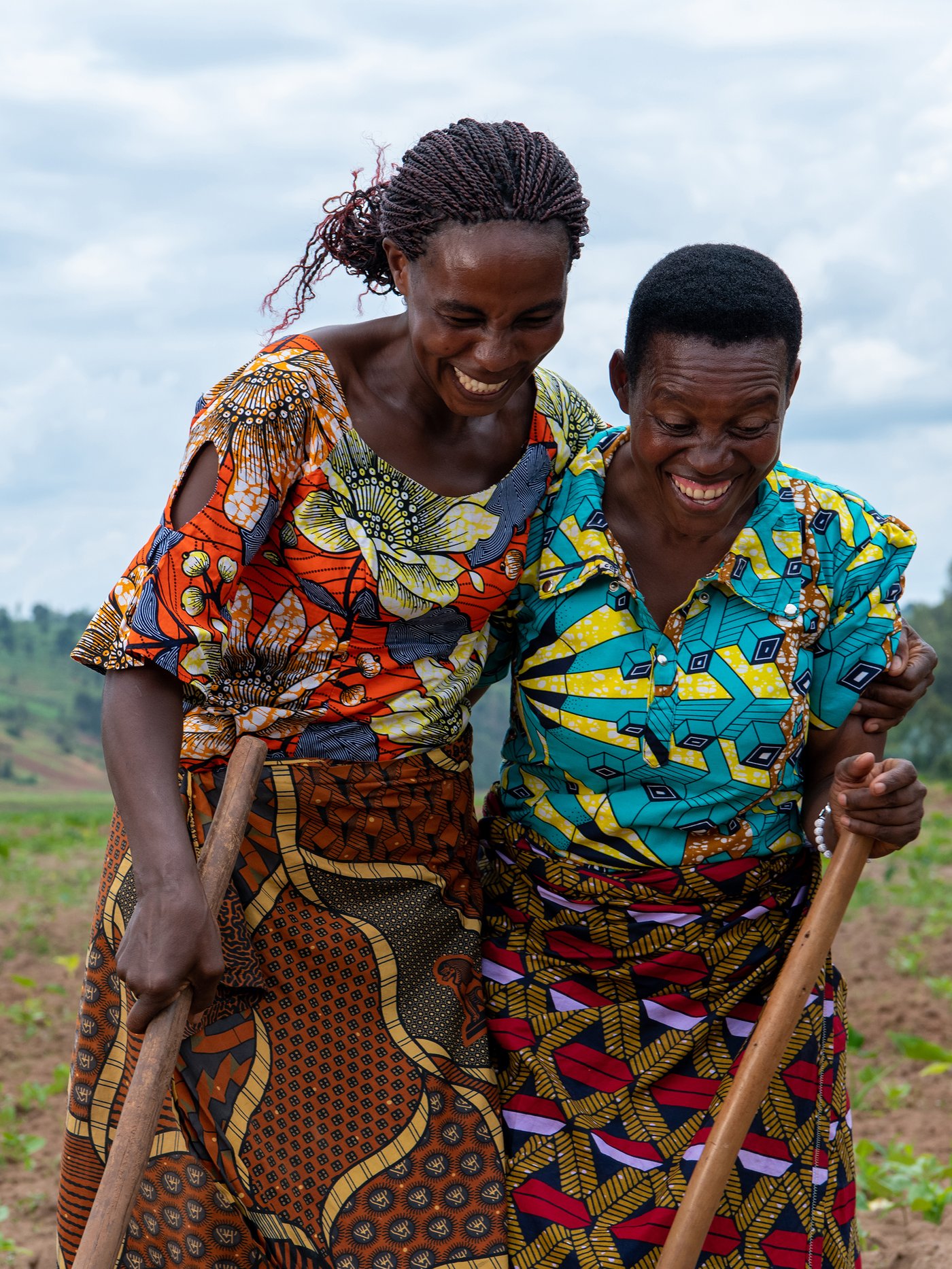 Two people stand hugging each other, laughing and wearing colourful patterns.