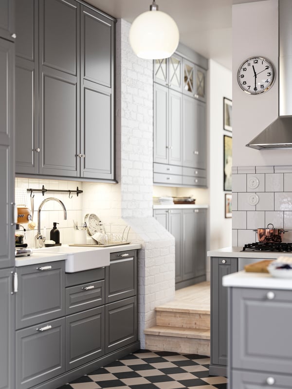 A kitchen with grey BODBYN fronts and a white HAVSEN sink bowl with visible front leading into a hallway with more cabinets.