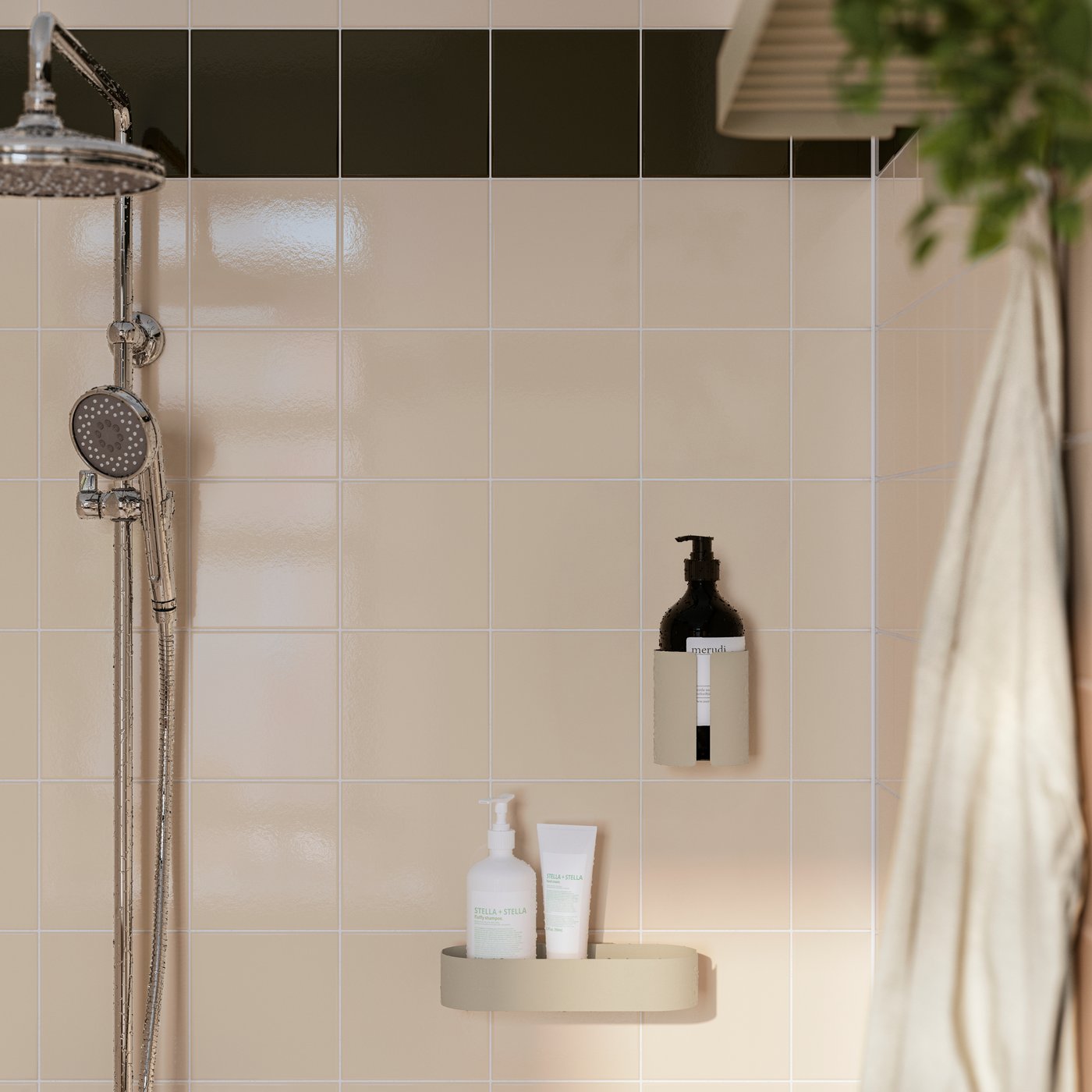 An einer gefliesten Wand ist neben einer Dusche eine FLORSJÖN Duschablage in Graubeige mit Flaschen zu sehen. Daneben ist ein passender Seifenspenderhalter platziert.