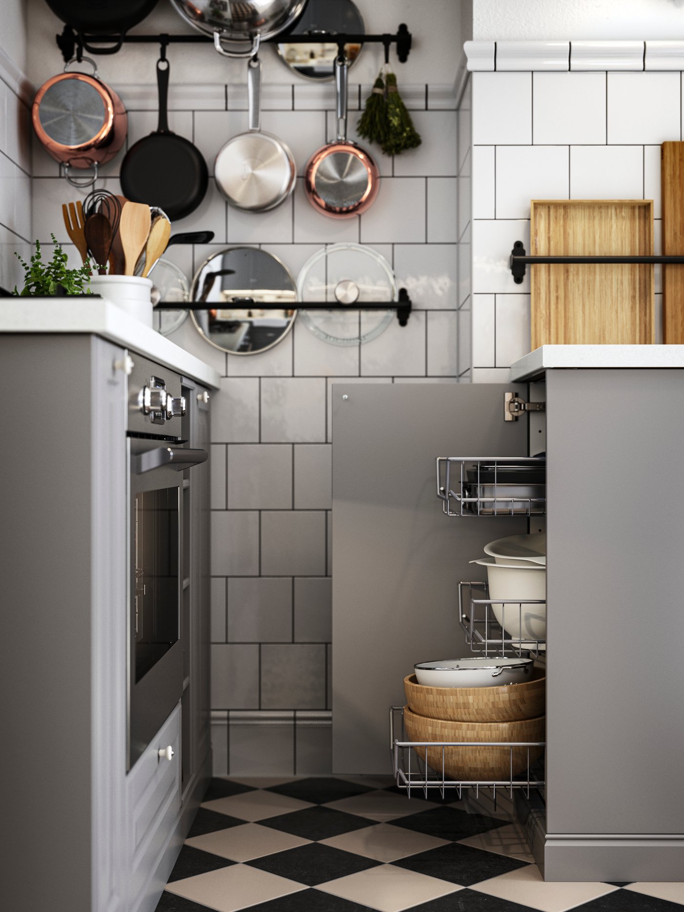 Szafka dolna z otwartymi drzwiami i wysuniętymi koszami z siatki obok płyty grzewczej i piekarnika w kuchni z szarymi frontami BODBYN.