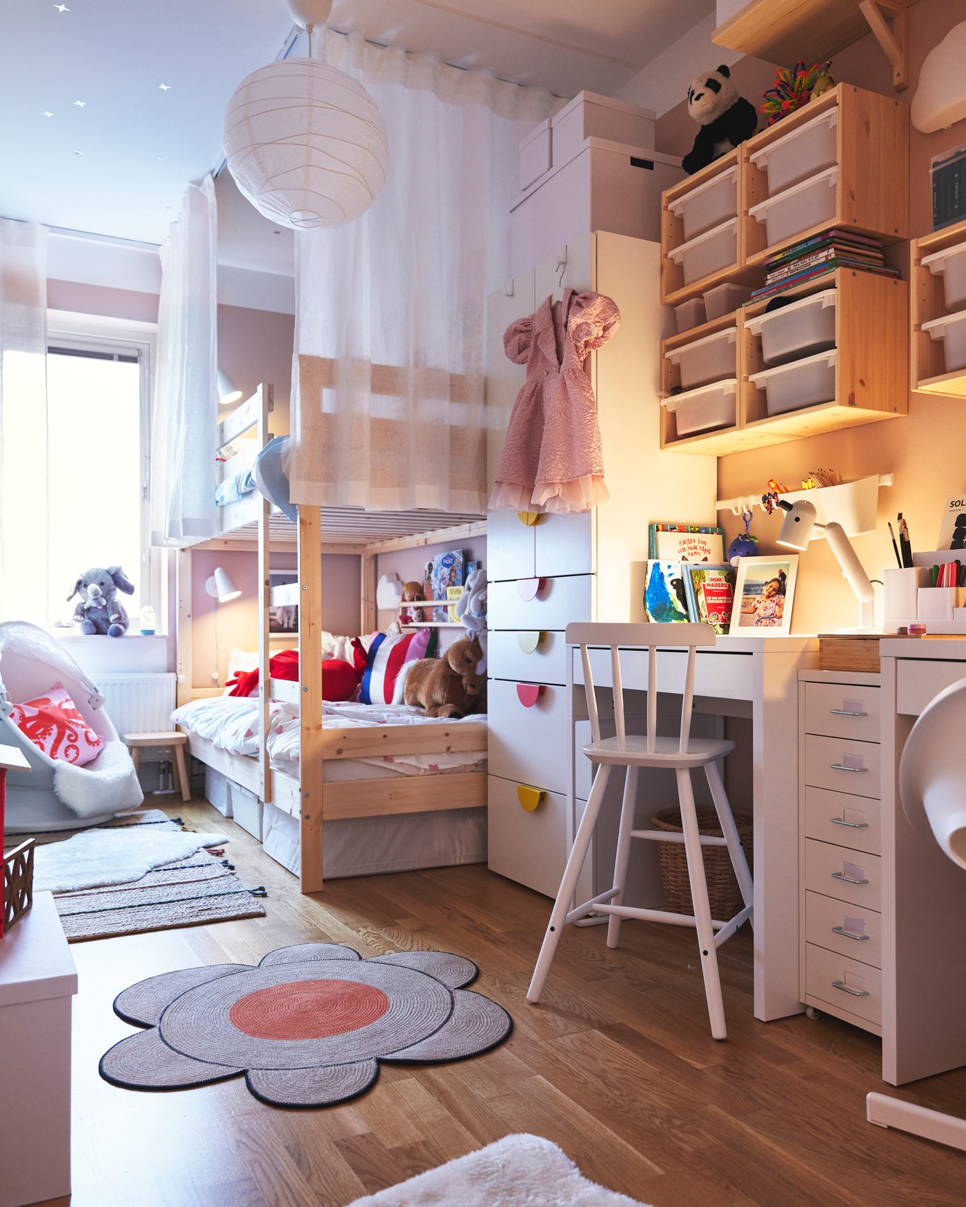 Ett delat barnrum i rosa och ljusa färger med en MYDAL våningsäng längst in i rummet.