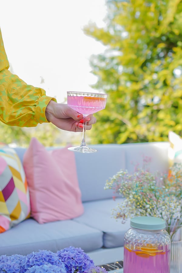 Kristin Gjelsvik holder et champagneglass med rosa leskende drikke.
