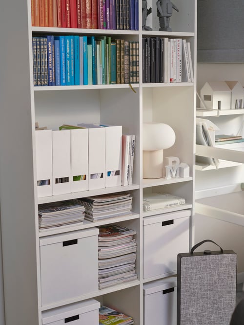 Étagère VIHALS avec livres, boîtes pour magazines, boîtes de rangement et éclairage. Un purificateur d’air est posé sur le sol.
