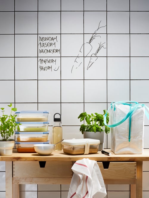 木製の作業台の上に、重ねられたIKEA 365+ ガラス製食品保存容器、バッグ、ハーブ。背景はホワイトのタイル。