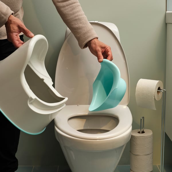 A woman emptying the turquoise removable insert from the white LOCKIG children’s potty into the toilet.