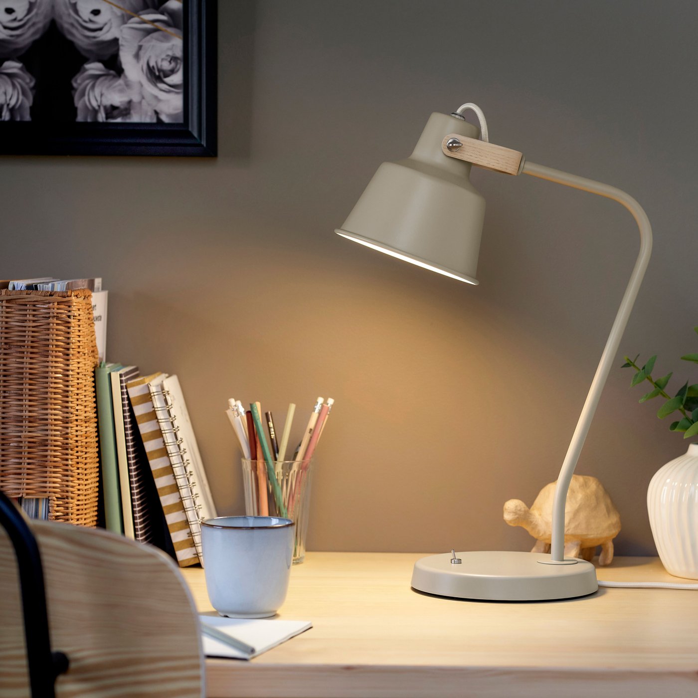 Een lichtgevende beige SJÖMAKT bureaulamp op een bureau.