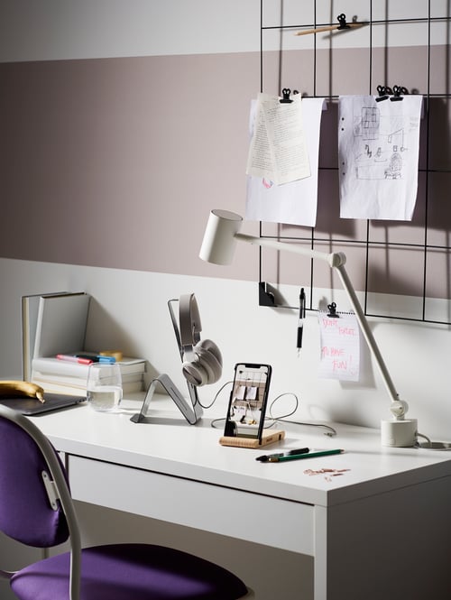 Desk with work lamp, BERGENES mobile or tablet holder and MÖJLIGHET headset or tablet stand with memo board on wall.