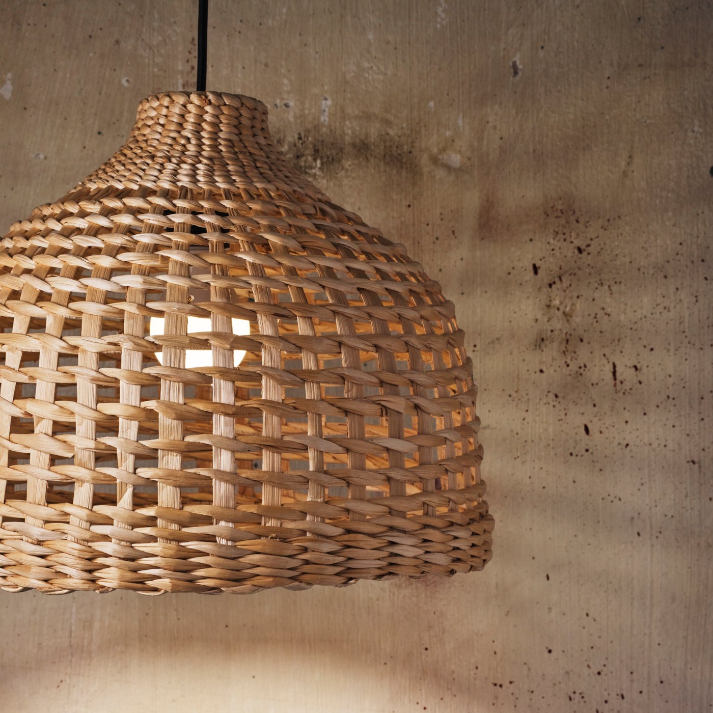 The handwoven MÄVINN lampshade made with banana fibres hangs from the ceiling with a black HEMMA cord set.