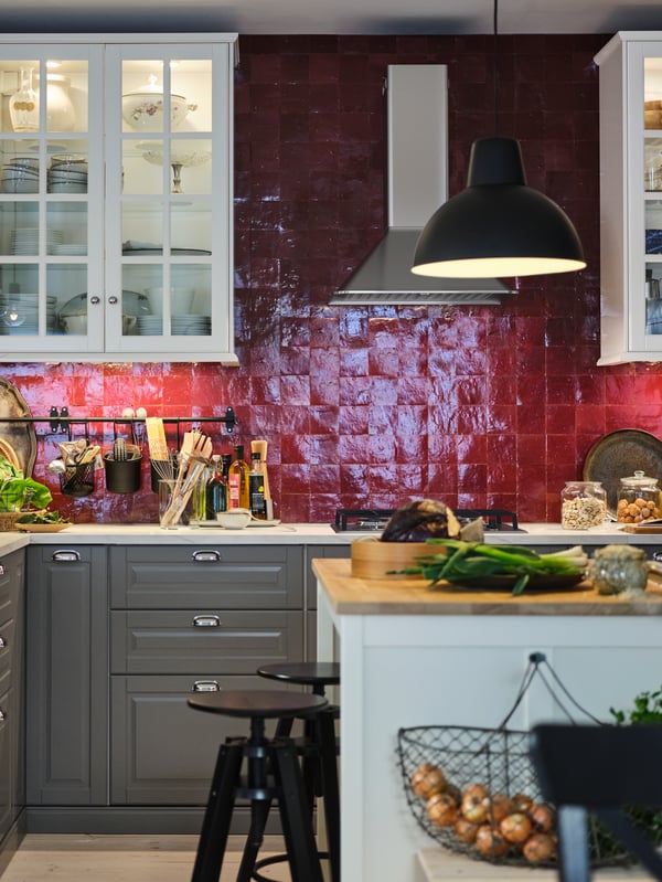 A tiled kitchen with white wall cabinets, grey base cabinets, white worktop and a white island with a natural-wood worktop.
