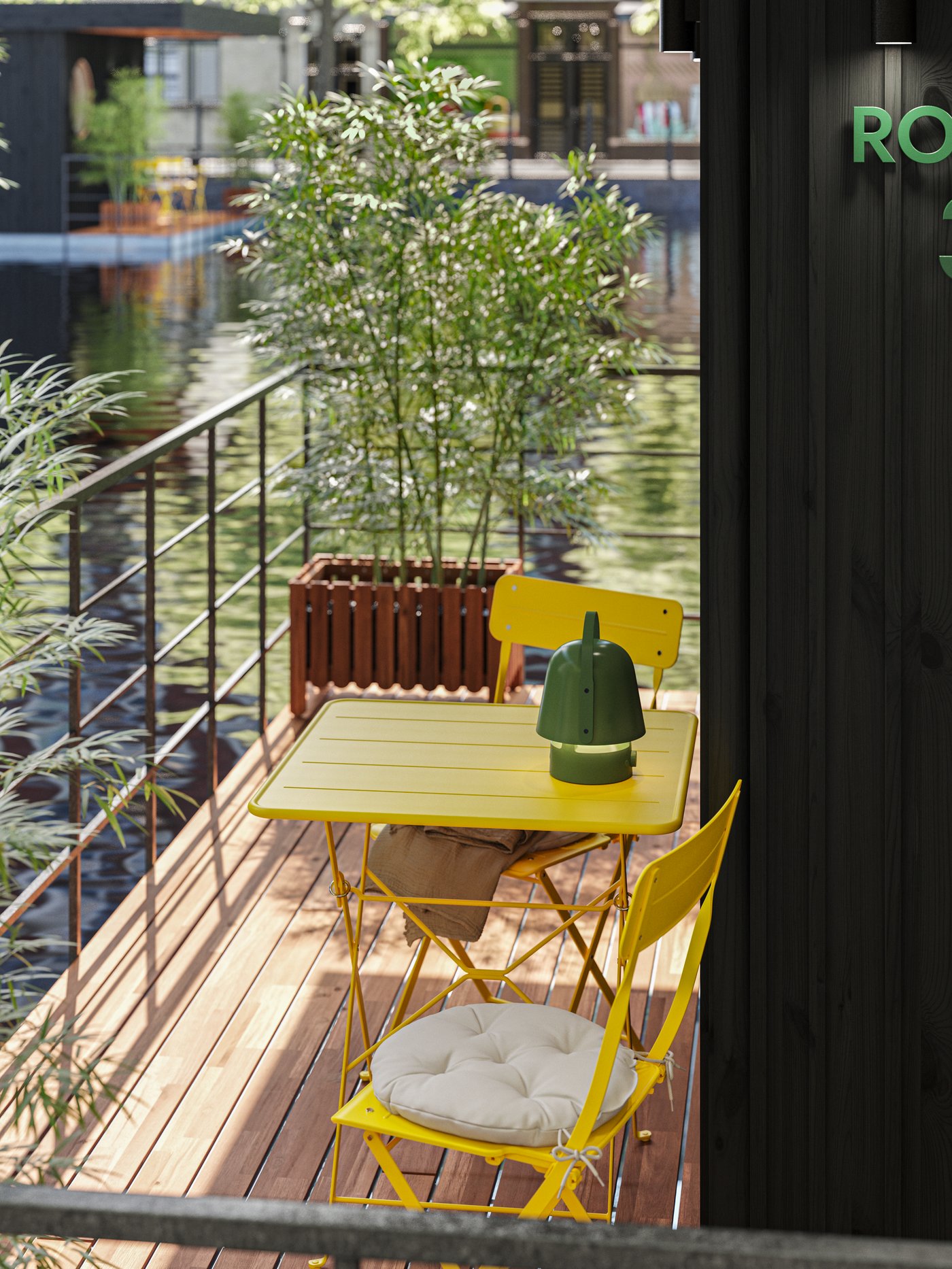 A houseboat patio overlooking the water. Two bright yellow SUNDSÖ outdoor chairs and table and a plant next to a rail.