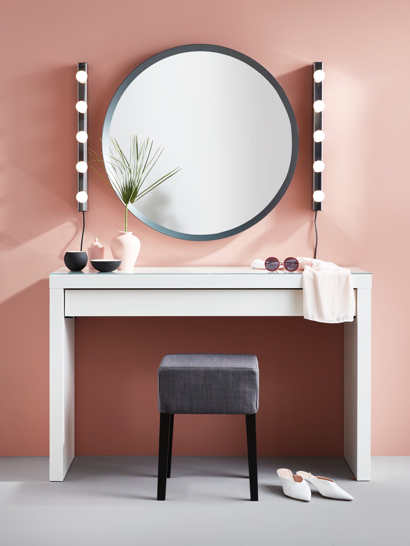 En sminkstation vid en rosa vägg.