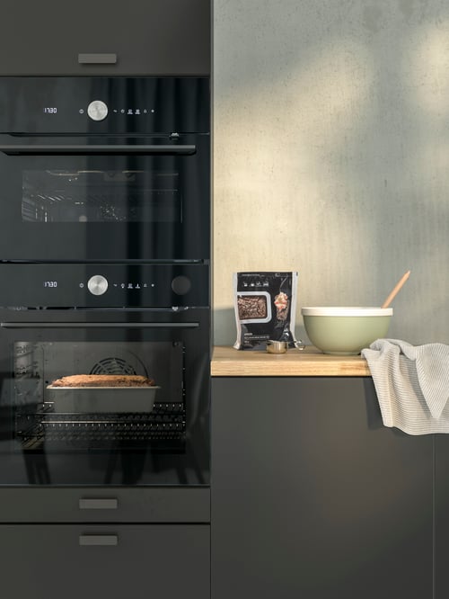 Pâine care se coace într-un cuptor cu convecție FINSMAKARE. Cuptorul este amplasat lângă un blat pe care sunt așezate un bol și un pachet de amestec pentru copt pâine.