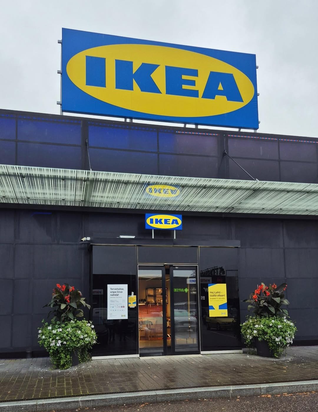 IKEA-myymälän sisäänkäynti sateisena päivänä, sinikeltainen logo näkyy rakennuksen yläosassa.