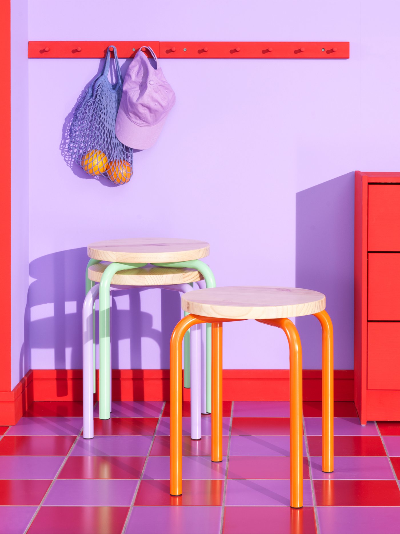 Stools from IKEA in different colors in a purple room with a red and blue floor.