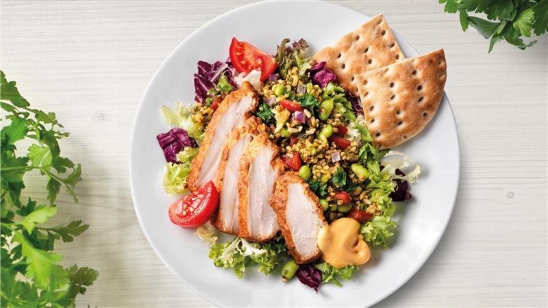 Salat mit Hühnerbrust und Quinoa auf einem Teller präsentiert.