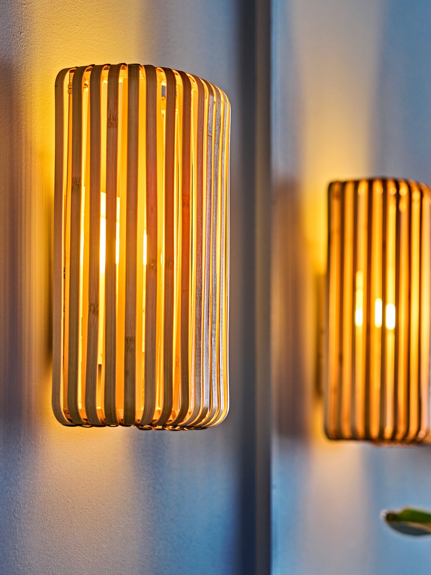 A blue living room wall with warm glow from three bamboo VARPTROSS wall lamps.