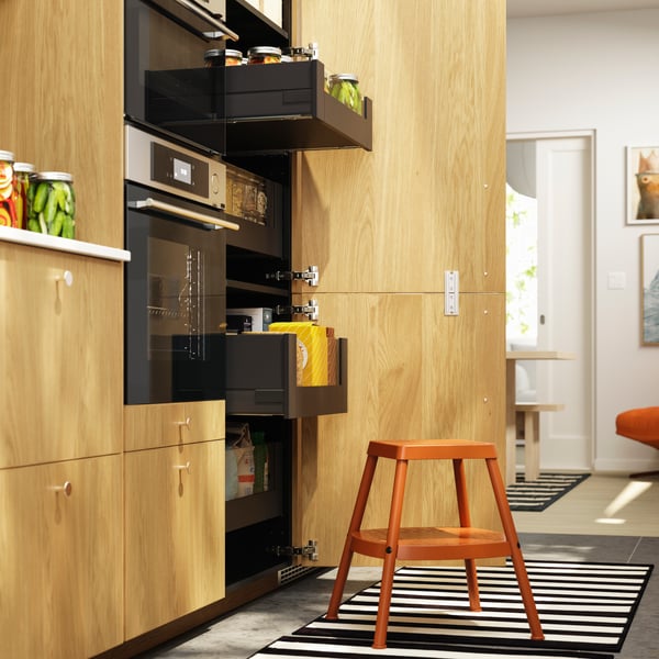 A kitchen cabinet door is open and two KNIVSHULT drawers have been pulled out, filled with food packages and food jars.