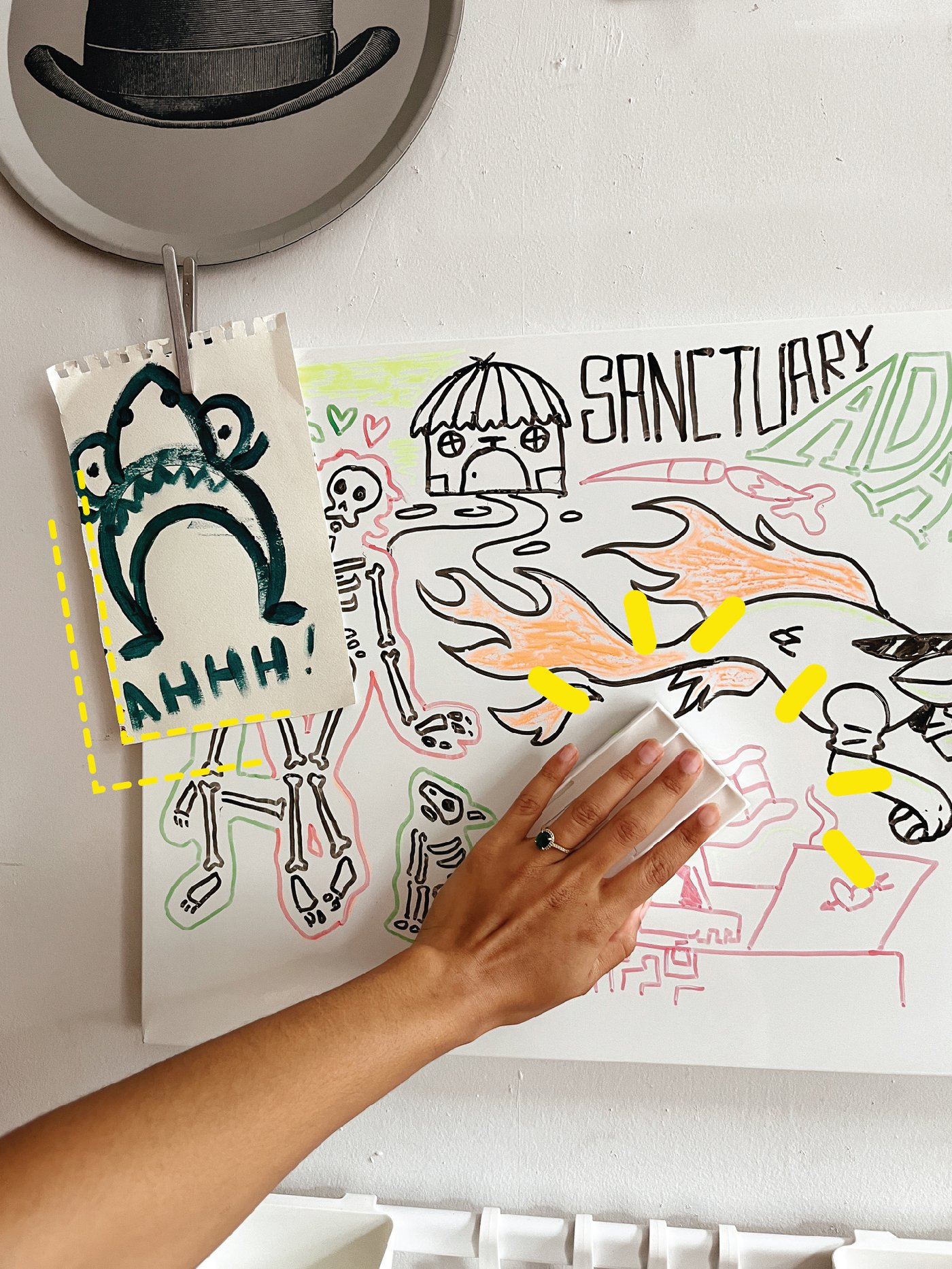 A hand wiping away notes from a whiteboard, with a drawing of a cartoonish shark pinned on top of it.