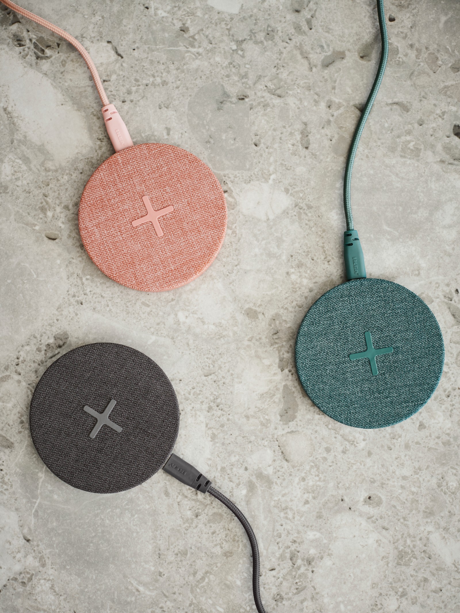 Tres cargadores inalámbricos de color rosa, azul y negro sobre un mostrador