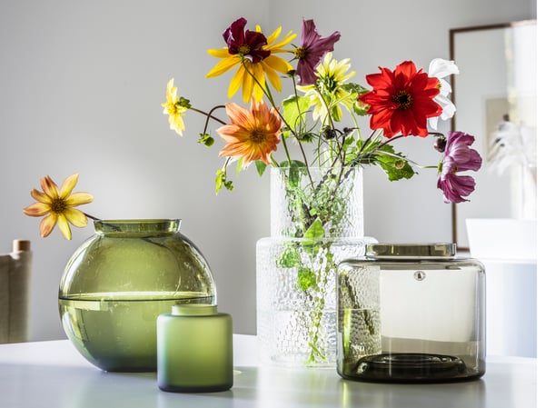 Mehrere KONSTFULL Vasen. In zwei Vasen befinden sich bunte Blumen.