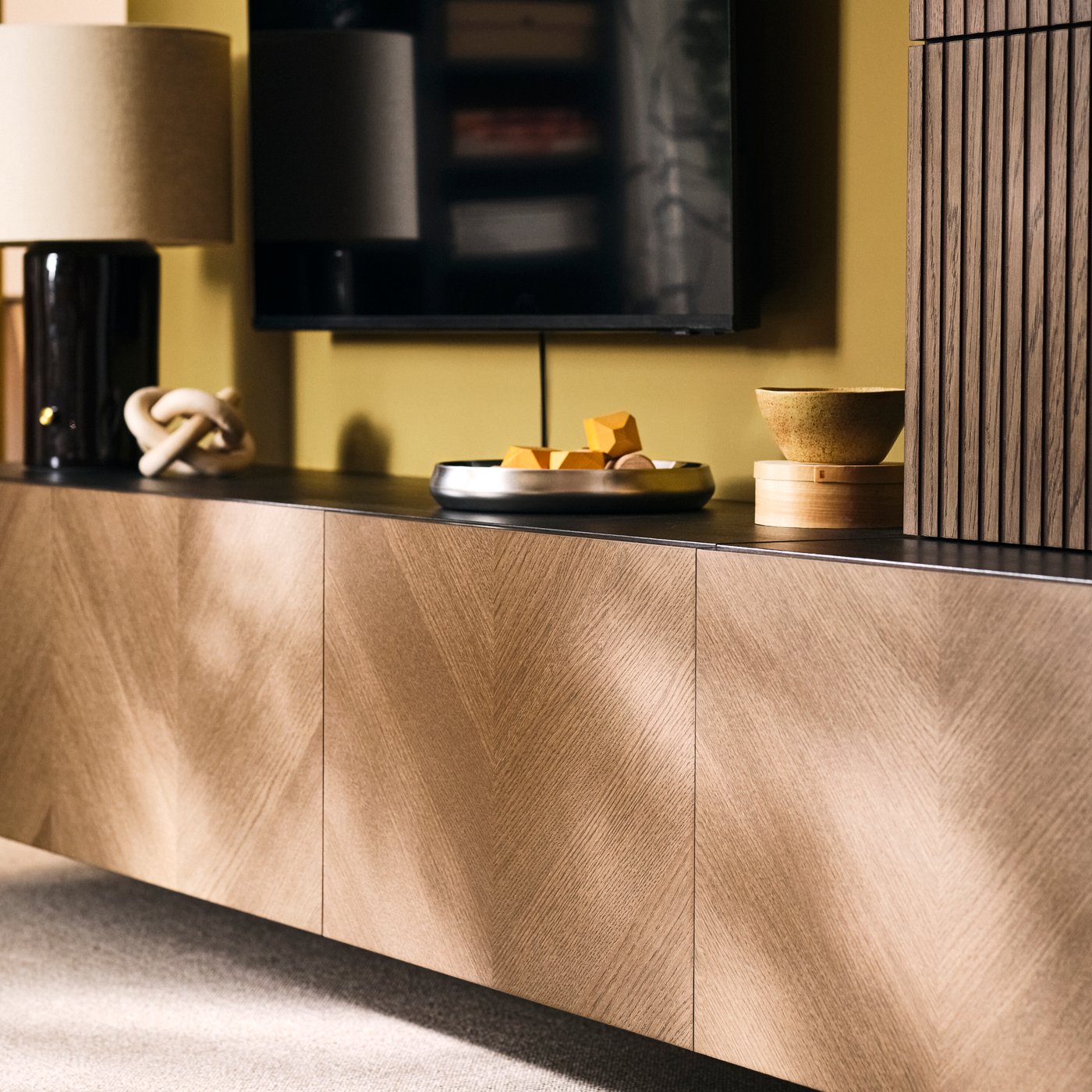 BESTÅ media storage combination with closed cabinets and decorative items beneath a TV in a living room.