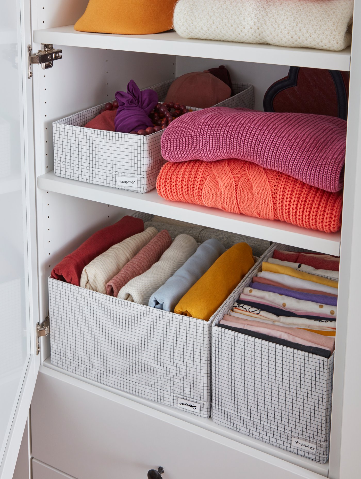 Clóset con cajas de almacenamiento STUK con ropa. Se ven 3 tamaños diferentes de cajas y ropa al lado de éstas.