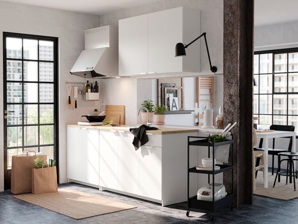 Cocina blanca KNOXHULT junto a carritos de cocina negros.