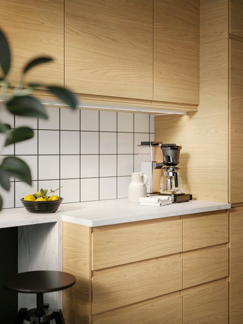 Kitchen with multiple beige VOXTORP doors, a white EKBACKEN worktop, multiple VOXTORP drawer fronts and a DALFRED bar stool.
