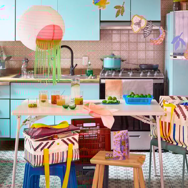 Dos tazones negros de ÖMSESIDIG para servir, de cerámica, llenos de chiles y nachos sobre una mesa de cristal coloreado. 