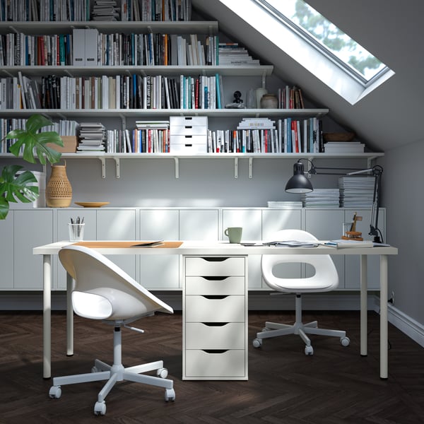 A white ALEX drawer unit supports a long desktop that has two chairs and work areas. The desk is in a modern home office.