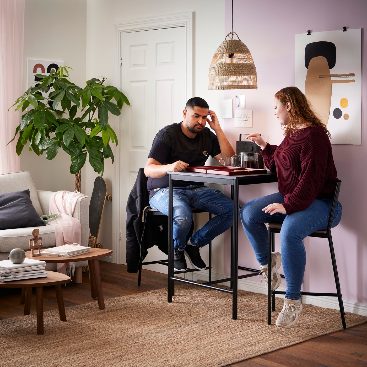 Een stel speelt een gezelschapsspel aan een hoge zwarte tafel in de kleine woonkamer.