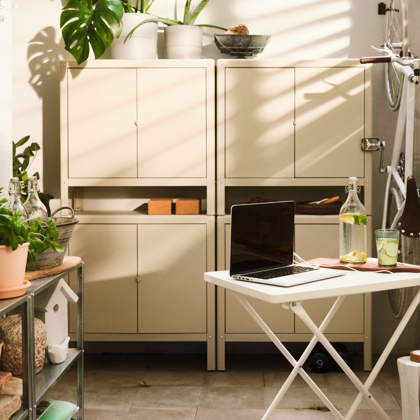 An einer Balkonwand steht ein grosser KOLBJÖRN Schrank in Beige, der sich aus zwei nebeneinanderstehenden Schränken sowie zwei darauf gestapelten Schränken zusammensetzt.