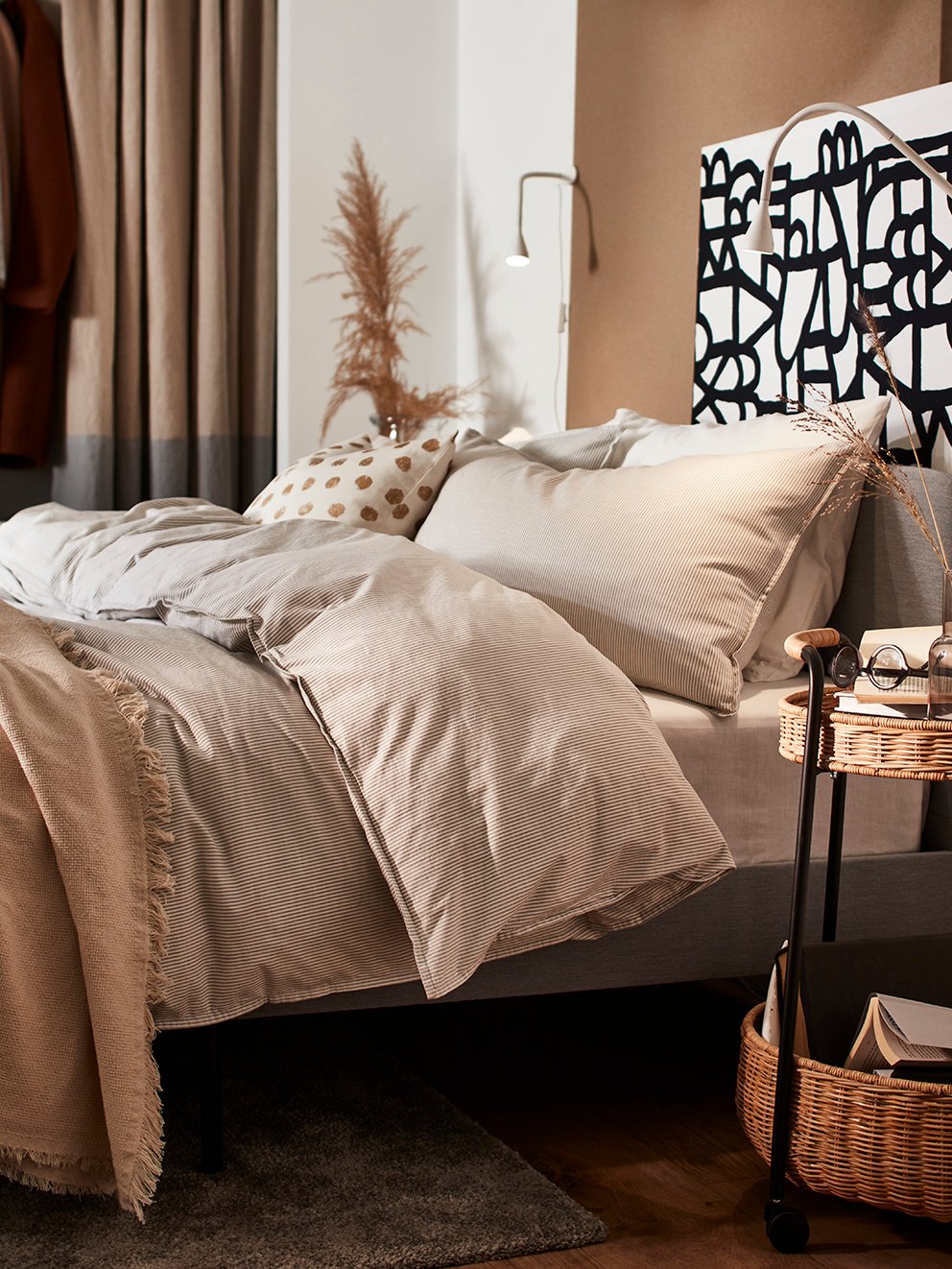 Une desserte LUBBAN à côté d'un lit rembourré SLATTUM avec literie, dont les draps BERGPALM.